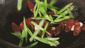 先后下香腸片、四季豆絲均勻翻炒，加適量清水燜煮一下。