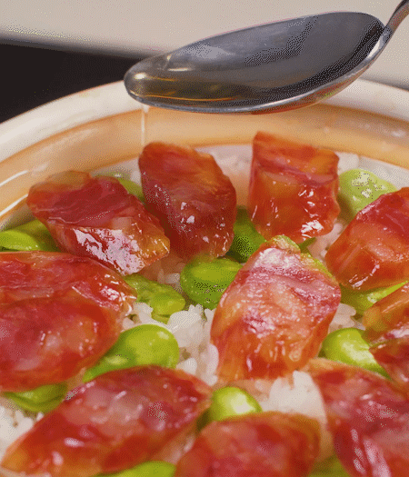 大米出現(xiàn)小孔時開蓋放香腸，往鍋邊淋入少許油，再燜煮8~10分鐘左右。