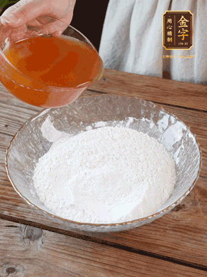 轉(zhuǎn)化糖漿、枧水、花生油攪拌均勻，加入面粉混合，醒發(fā)2小時(shí)。捏成23g一個(gè)的小球