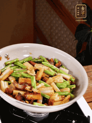 油熱下蒜末、干辣椒、醬肉煸炒出香味，依次下藕條、豆角翻炒均勻
